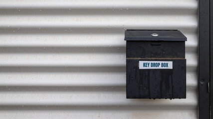 Key drop box and sign.  Wet, exterior of modular, transportable, temporary building used in the mining and construction industries. Copy space. Leading lines