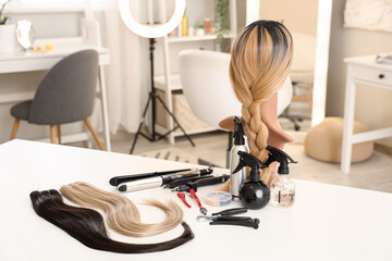 Mannequin with wig and hair extension tools on table in beauty salon