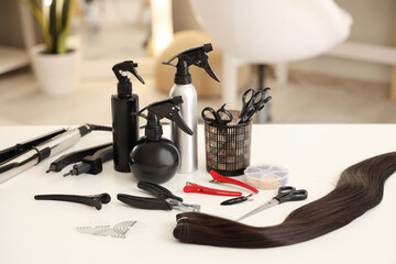 Hair sprays with extension tools on table in beauty salon, closeup