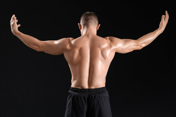 Fototapeta premium Male bodybuilder on dark background, back view
