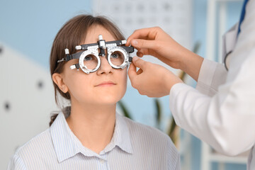 Female ophthalmologist putting trial frame on patient in clinic, closeup