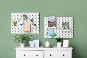 Stylish living room with white chest of drawers, houseplant, photo frames and pegboard