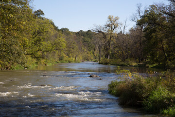 Winding River with Blue Sky and Reflections in Lush Green Landscape with Trees Horizontal