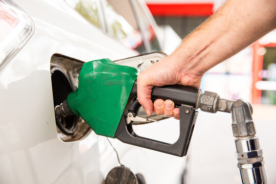 close up of a person refuelling a car with a green petrol pump