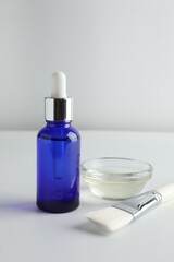 Bottle of chemical peel, bowl with liquid and brush on light background. Peeling procedure