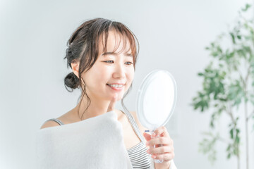 鏡で歯をチェックするアジア人女性（インプラント・ホワイトニング・歯列矯正）
