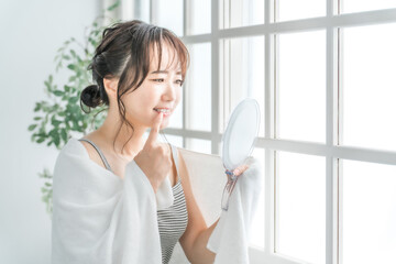鏡で歯を見て困るアジア人女性（虫歯・歯並び・歯周病）
