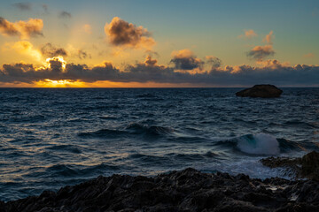 A beautiful sunrise on the north shore of Oahu, Hawaii casts golden rays above Laie Point.