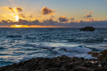 Fototapeta premium Waves crash against rocks at sunrise on Oahu's north shore at Laie Point.