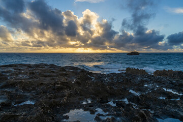 Sunrise at the rocky beach in Laie, Hawaii as clouds float in.