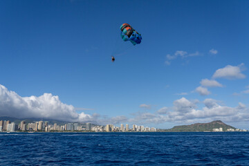 Parasailing near Honolulu and Waikiki beach with a blue sky and Diamond Head as a backdrop is fun recreation for any tourist.