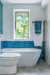 A bright bathroom with white walls and grey floors, featuring blue subway tiles on the wall behind the toilet and bathtub