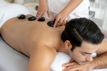 Hot stone massage at spa salon in luxury resort with day light serenity ambient, blissful man...