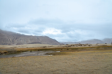 The valley between mountains on a cloudy day. A dried river terrain of Shyok river in Nubra Valley in Ladakh Region of Indian Himalayan territory.A Barren landscape of Cold dessert in Himalaya Valley.