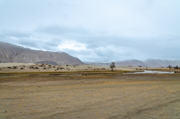 The valley between mountains on a cloudy day. A dried river terrain of Shyok river in Nubra Valley in Ladakh Region of Indian Himalayan territory.A Barren landscape of Cold dessert in Himalaya Valley.