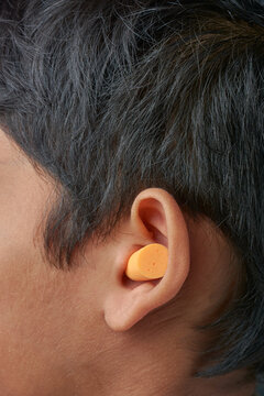 disposable soft expandable foam earplugs inserted into ear, wearing single use uncorded and comfortable hearing protection used in workplace, concerts and sleeping, selective focus with copy space