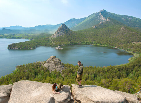 It is a resort of Borovoe. There are two people on the foreground. There is a Burabay lake on the middle of frame. There is a mountain Kokshetau on the background.