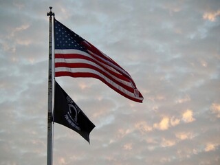 United States and POW flags against a sky of cirrocumulus clouds over El Dorado, Kansas. 
