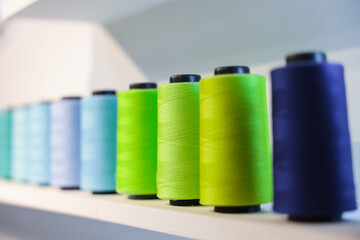 Colorful Spool of sewing thread on the white shelf, isolated on white background. Colored yarns used by factories in the clothing industry. Threads wound on the spool. Colored reels