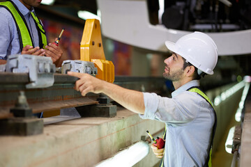 Engineers or technicians checking railroad with coworkers and pointing to something at train station construction site