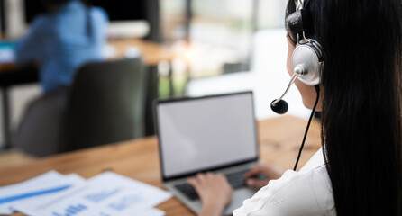 Rear view of Young  operator woman agent with headsets working in a call centre.