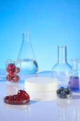 Front angle photography over blue background, plenty experiment tools neatly arranged on the table with fresh cherry and blueberry. Vacant white podium in round shape, copy space for adding text
