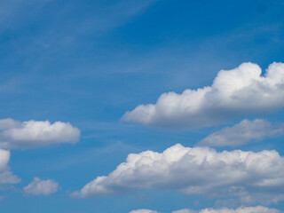 Clear Blue Sky with Fluffy White Clouds Against Daylight Background