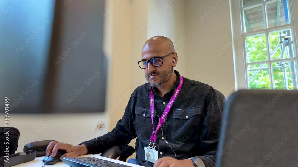 Poster a man eagerly works in an office setting, sitting in front of screens and using a keyboard, embodyin