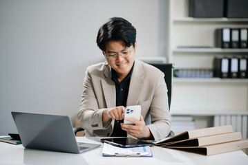 Fototapeta premium Young businessman working with working notepad, tablet and laptop documents talking on the smartphone, tablet and laptop