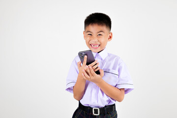 Portrait smiling Asian little boy primary posing holding a cell phone studio isolated white background, happy cute man kid wear school uniform hold smartphone enjoying himself, back to school concept