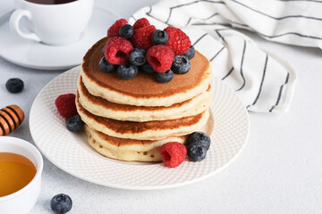 Pancakes with raspberries and blueberries on a light background for breakfast