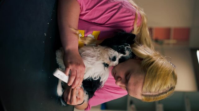 vertical video close up In the grooming salon a small white-black dog by the groomer nail trimming procedure