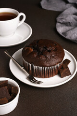 Chocolate muffin on a dark background with a cup of tea.Brownie cupcake