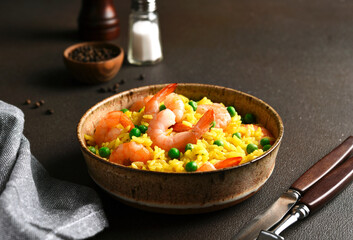 Rice with shrimp and green peas on a dark background