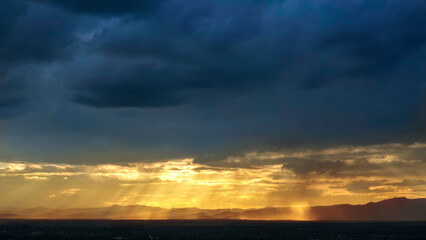 Obraz premium Beautiful sunset over the hill and city with vibrant orange and blue hues in the sky, Sunset in the mountains with sun rays and clouds