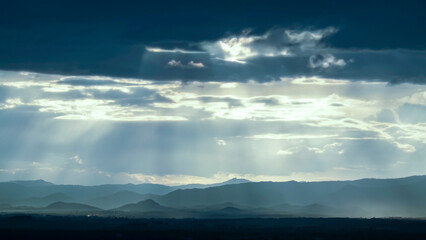 Beautiful sunset over the hill and city with vibrant orange and blue hues in the sky, Sunset in the mountains with sun rays and clouds