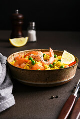 Rice with shrimp and green peas on a dark background