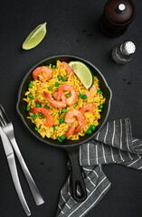 Rice with shrimp and green peas on a dark background