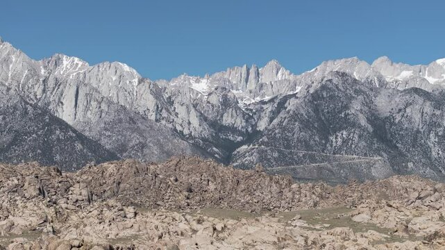 Aerial ped down of Mount Whitney, California with Alabama Hills in the foreground on a sunny day.