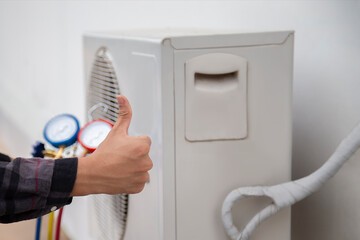 Air conditioning, HVAC service technician using gauges to check refrigerant and add refrigerant.	