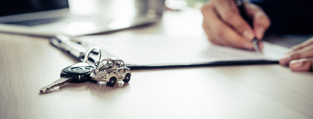 close up shots hands of client signing car lease form.