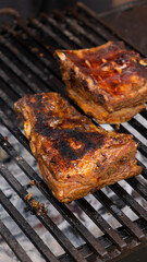 Marinated pork ribs are cooked on the coals of a barbecue