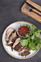 A plate of fried pork ribs with sauce and greens