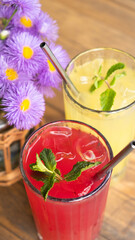 Colored summer lemonades with ice and mint on wooden table