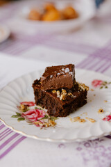 Chocolate brownie topped with ganache and sea salt on a floral plate.
