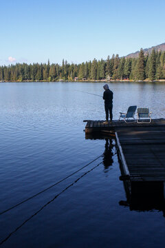 Person fishing on a dock at Lake Sacheen, surrounded by trees
