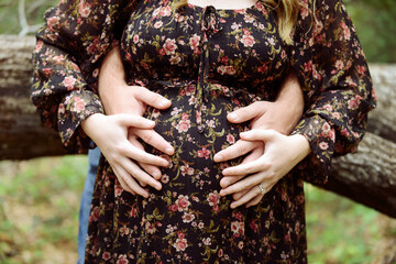 Close-up of a pregnant woman in a floral dress with couples hand