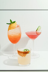 Three colorful summer cocktails with garnishes.