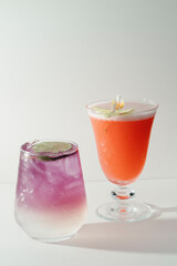 Two vibrant cocktails, one purple, one orange.