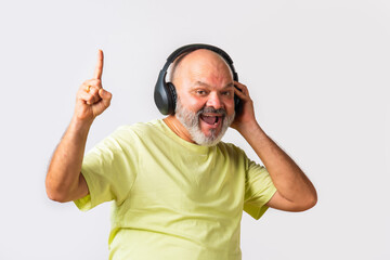 Fototapeta premium Senior elderly retired Indian asian man wears headphone and listening to music and dancing on beats against white background